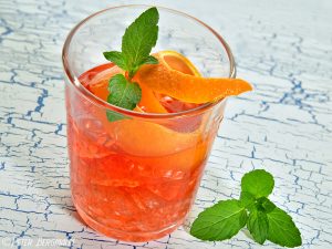 Summer Cocktail »Negroni« mit Minzeblatt und Orangezeste dekoriert